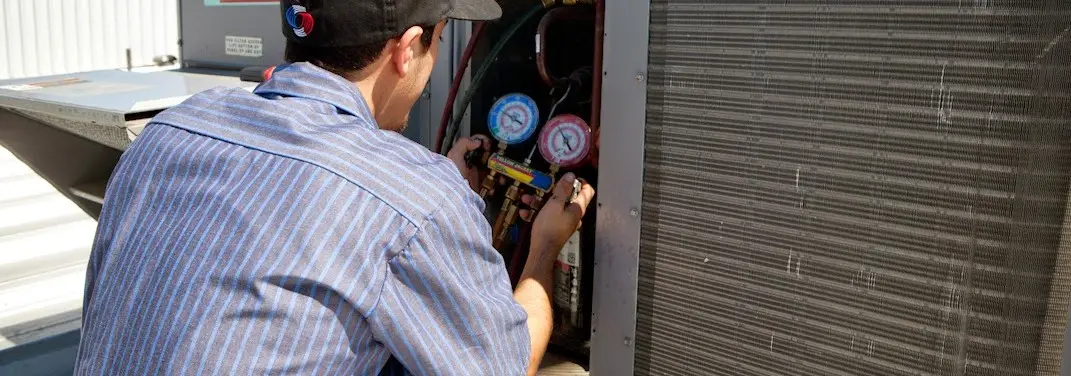 HVAC technician servicing a condenser unit in Massillon